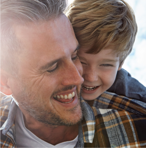 Happy boy cuddling smiling man.