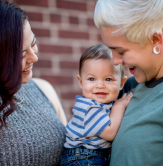 Happy carers holding child.